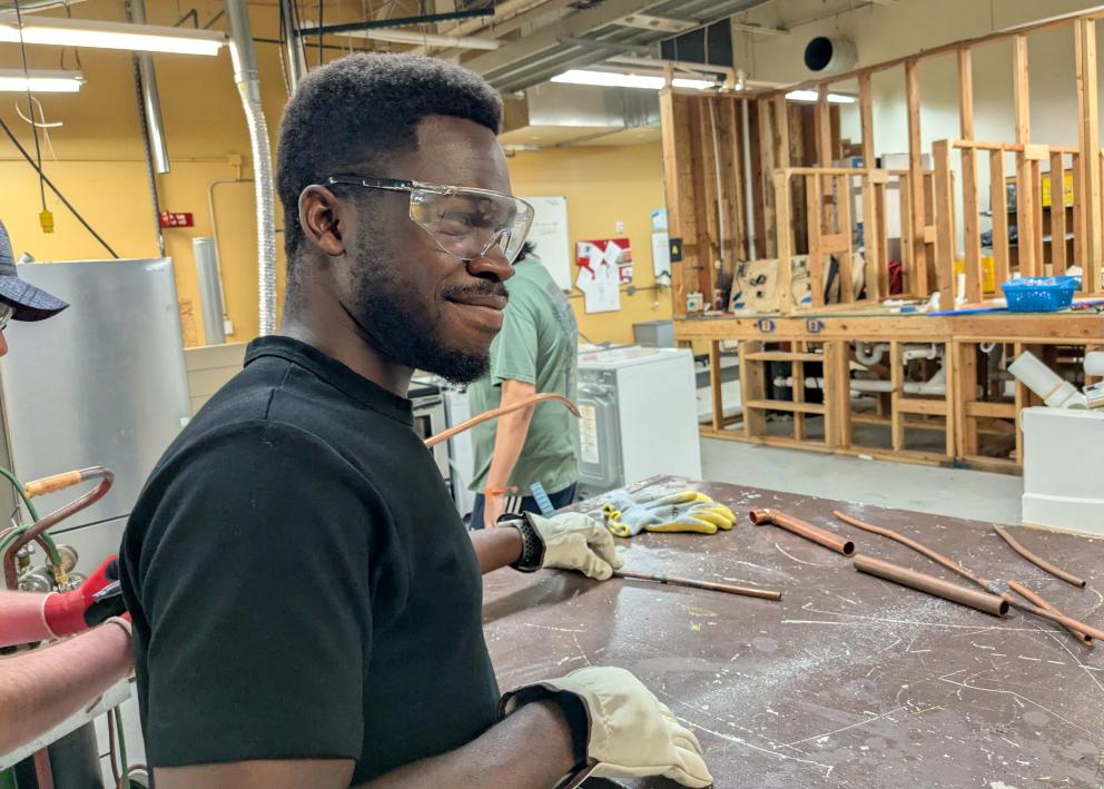 A student smiling wearing safety goggles and gloves