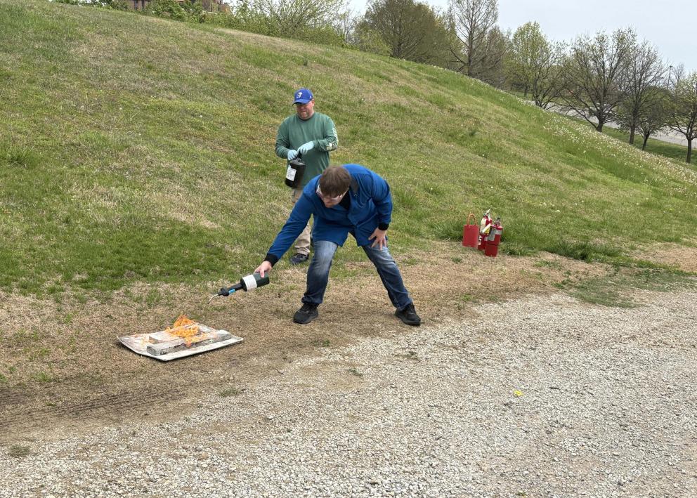 A person starting a small fire by the side of a gravel road