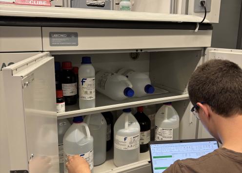 A person checking a cabinet full of chemicals